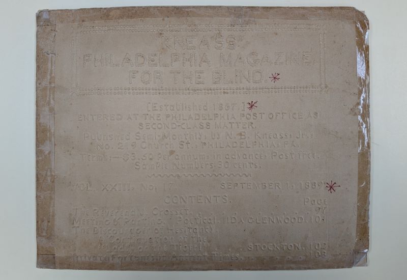 The cover of a book shows raised letters reading Kneass’ Philadelphia Magazine for the Blind